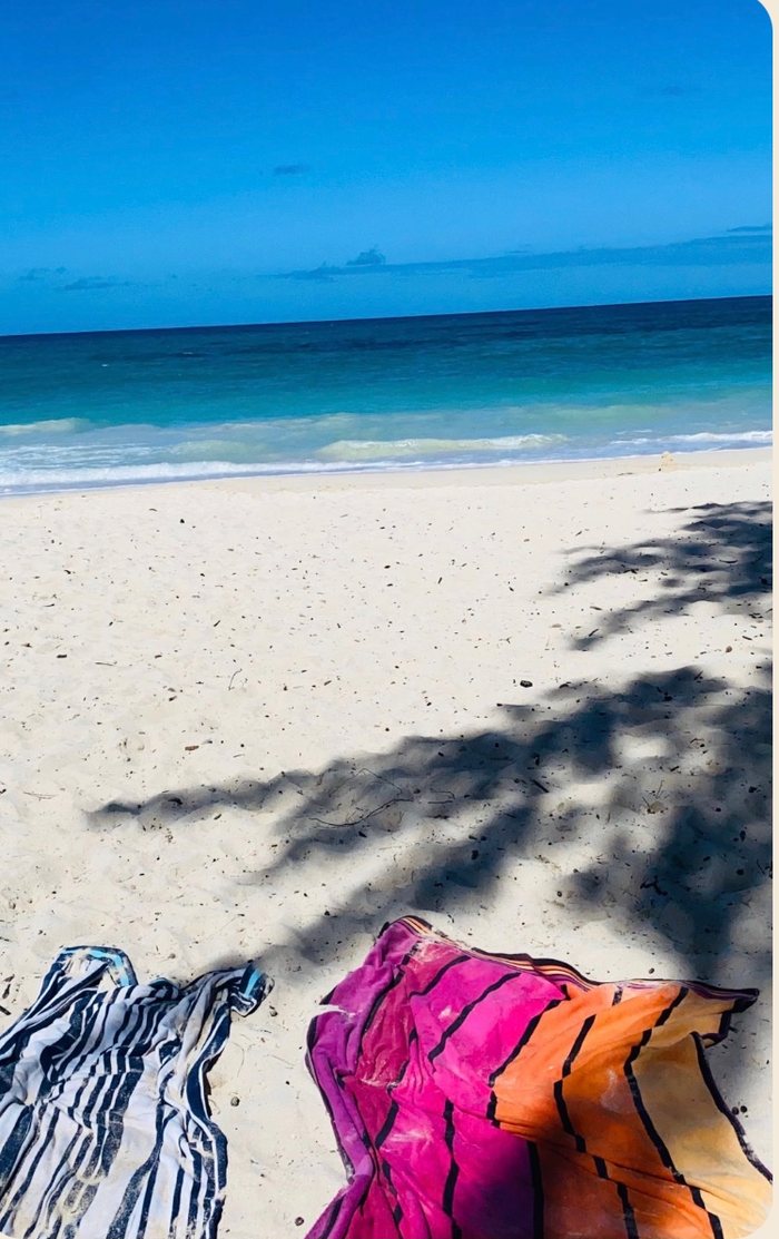 A bright Hawaiian beach with turquoise water and a beach towel in the shade